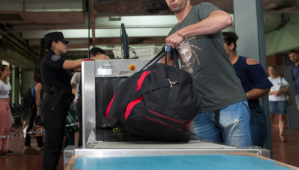 hombre con valija en escáner de aeropuerto