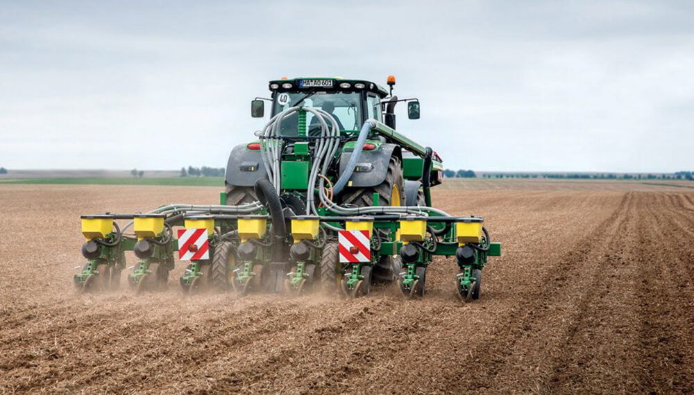 máquina agrícola sembrando maíz en un campo